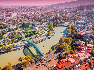 Tbilisi cityscape capturing the river Mtkvari, famous architectural landmarks, and autumn foliage from an aerial perspective © EdNurg
