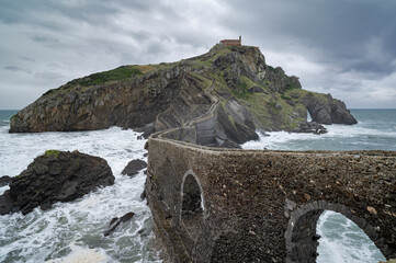 Dramatic view of San Juan de Gaztelugatxe islet and bridge under a cloudy sky.