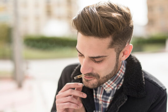 Handsome man smoking cigar in street