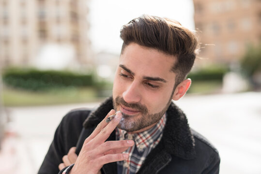 Handsome man smoking cigar in street