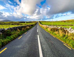 An asphalt road stretches towards the horizon, bordered by stone walls and green fields under a dramatic, cloudy sky