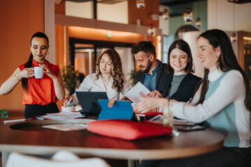 Colleagues gather around a round table, collaborating with laptops and documents in a bright modern office. Coworkers share ideas and review charts, creating a dynamic teamwork environment.