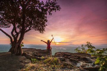 Young woman hiking on high mountain with beautiful sunset on Pha Daeng viewpoint, Na Yung Nam Som National park, Udon-Thani province , Thailand.