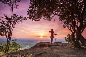 Young woman hiking on high mountain with beautiful sunset on Pha Daeng viewpoint, Na Yung Nam Som National park, Udon-Thani province , Thailand.