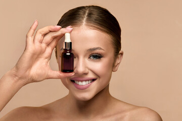 Beauty woman holds serum bottle in front of her face in studio for skincare routine during a...