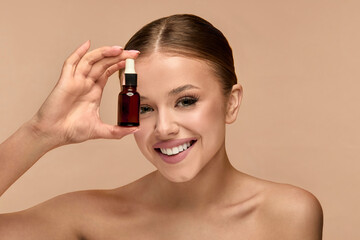 Beauty woman holds serum in studio for skincare routine focusing on glow and health of the skin...