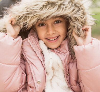 6 year old pretty girl with winter coat smiles and looks at camera