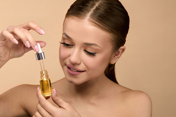 Beauty woman holds serum bottle while applying skincare for healthy skin in studio setting with...