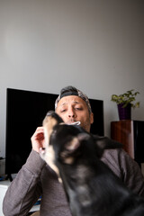 A man is brushing his teeth while a dog looks on