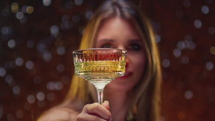 Female holding a glass of champagne. Girl is enjoying birthday party or New Year. Woman holds sparkling wine in palm, clinks her glass and makes a toast, congratulations. Cocktail creamers - le coupe