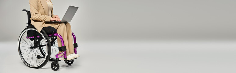 Obraz premium Businesswoman in formal wear working on a laptop from her wheelchair