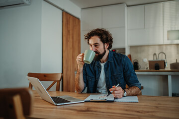 Man working from home drinking coffee and analyzing data