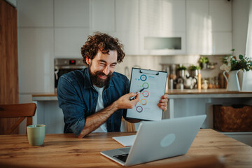 Obraz premium Bearded man discussing chart during home office video call