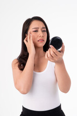 Self-Reflection: A woman examines her face in a compact mirror, revealing her concerns. Her expression captures feelings, a personal moment of self-assessment and contemplation.