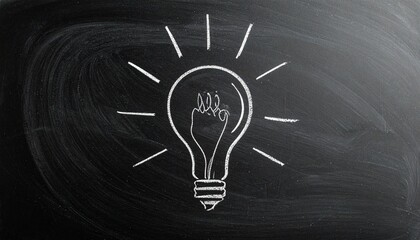 Chalk drawing of light bulb with fist inside on blackboard, radiating lines symbolizing empowered ideas and strength.