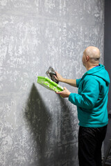 An experienced plasterer uses a trowel to apply decorative plaster to a wall, crafting a unique, textured finish, demonstrating skill in interior design and home improvement, with artistic flair.