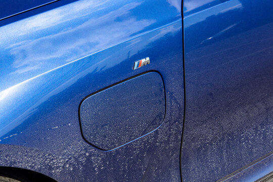 February 6, 2022, Seoul, South Korea - The charging port door and M badge on a dirty blue BMW M340i sedan covered in road salt.