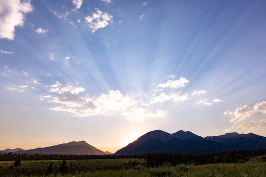 sunset over mountains with sun rays in blue sky