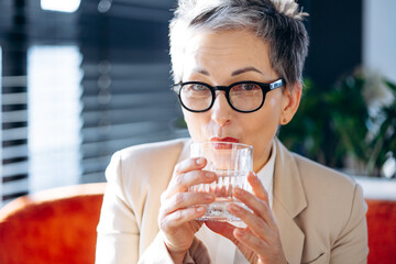 Woman drinking water and working on laptop in a cafe