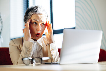 Business woman shocked while working on laptop in a cafe