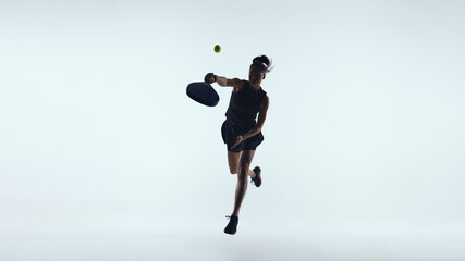 Female padel player jumping forehand shot isolated on white background. Concept of explosive movement, offensive play, dynamic footwork, power generation and high intensity padel action.