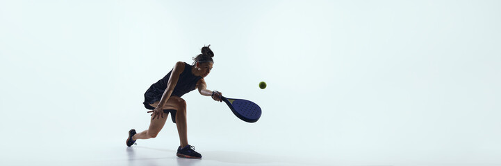 Padel player bends forward controlling ball close to floor. Concept of padel precision, technical play and promotional visuals for professional sport advertising. Banner