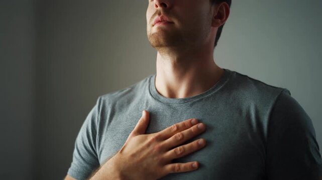 Young adult caucasian man holding his hand over his heart in a gesture of gratitude. A sequence of emotional moments showing faith, self love and inner peace concept