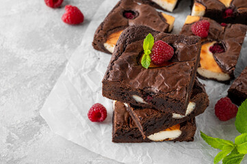 Cheesecake brownies with raspberry on a gray concrete background. Delicious dessert