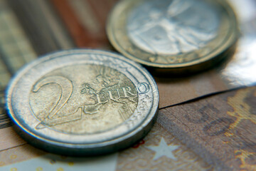 Close view of a two euro coin beside euro banknotes on a patterned surface showing details and textures