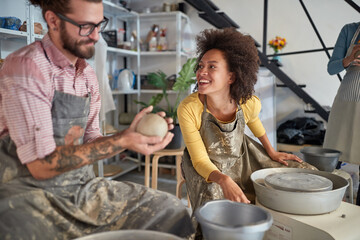 Group of people having fun on pottery workshop making pot from clay