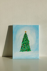 Hand painted Christmas tree artwork on canvas in cozy interior with sunlight