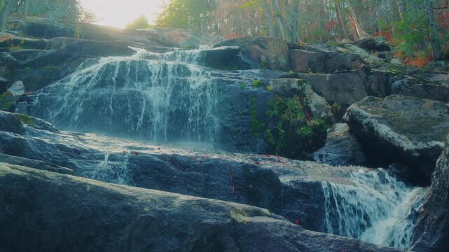 A beautiful, wide shot of Glendale Falls, a natural waterfall cascading over dark rocks in a lush forest setting in Middlefield, Massachusetts. The footage captures the serene beauty and natural lands