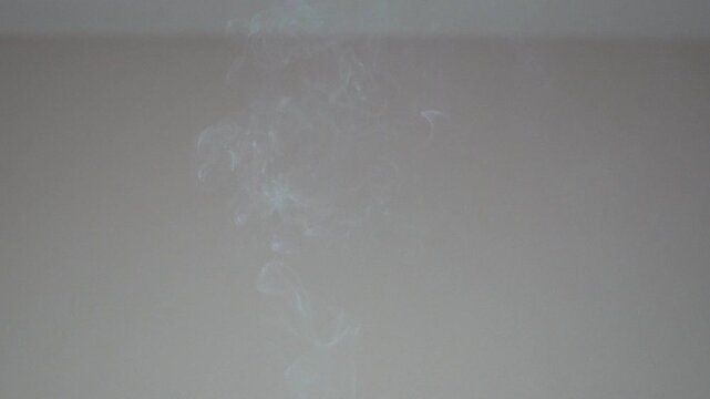 Smoke fluid rising up against a simple grey background creating laminar flow and dynamic abstract shapes for effect
