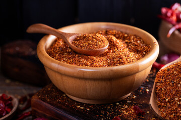 A close-up image of chili powder in a wooden spoon, spices for Asian cooking, arranged on a wooden table, conveying the concept of spicy food.
