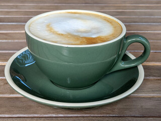 Green cup of hot coffee on the table