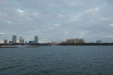 Obraz premium Coastal City Waterfront With Modern Buildings And Calm Vinoy Basin Under Cloudy Sky from the Pier in St. Pete, FL. Cityscape featuring modern high-rises along the shore, calm water, and a cloudy sky, 