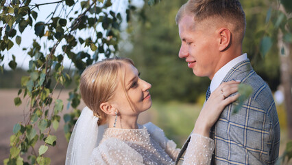 Fototapeta premium Loving newlyweds embracing beneath birch tree, wedding attire highlighting romantic connection and intimate celebration