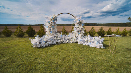 Round wedding arch decorated with white and blue flowers, ready for the ceremony in a beautiful outdoor location