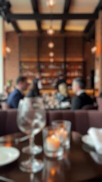Defocused background of a fine dining restaurant with blurred people, bokeh lights, and candles on a table, creating a warm and sophisticated atmosphere perfect for any out of focus concept