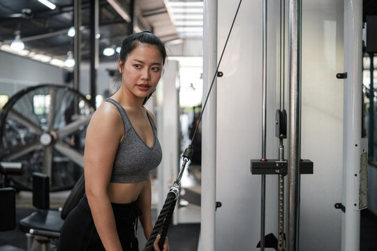 Focused young woman performing cable rope triceps pushdown in a modern gym. Healthy lifestyle concept.