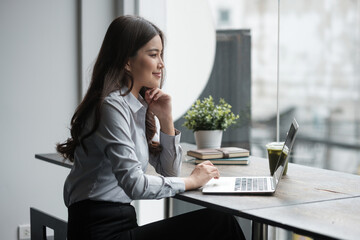 Professional woman in a gray shirt enjoying remote work at a stylish coffee shop.
