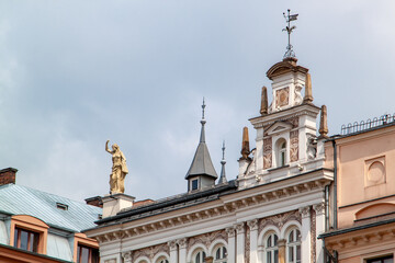 Obraz premium Ornate historical building facade with architectural statues and intricate detailing against cloudy sky, showcasing European urban architecture and decorative elements