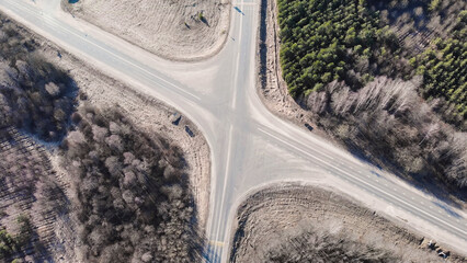 Aerial view of a road intersection near Trokiele church crossing a forest and fields in sunny spring day