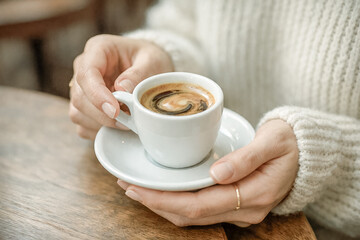 Female Hand Holding White Espresso Cup and Saucer on Wooden Table Cozy Knit Sweater Warm Coffee Morning Lifestyle Scene