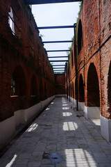 Obraz premium The corridor of an old building made of sturdy red brick. The long corridor forms a leading line. Perspective photo of the building. 