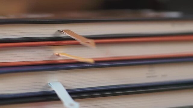 Soft cinematic shot of bookmarks inserted into stacked textbooks with shallow depth of field