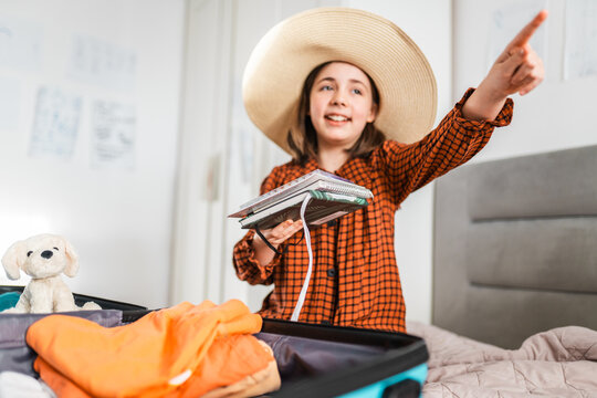 Child girl prepares her suitcase for travel.