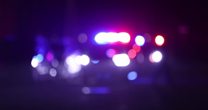 Abstracted illuminated night view of police units on a city street.