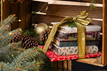 Obraz premium Festive Christmas Book Stack Gift with Golden Glitter Ribbon and Pine Branches