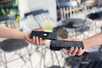 Contactless smartphone payment processing on mobile POS terminal at outdoor cafe, illustrating...